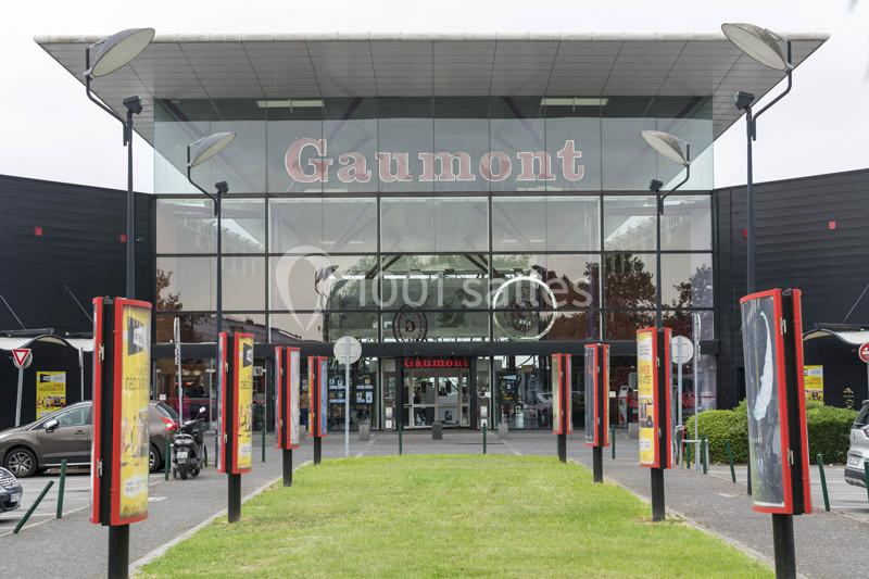 Façade vitrée d'un cinéma Gaumont avec affiches de films et entrée principale visible.