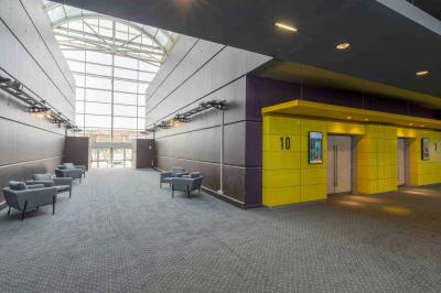 Miniature Location salle Coquelles (Pas-de-Calais) - Pathé Cité Europe #12 Couloir lumineux avec moquette grise, fauteuils, murs sombres, panneaux jaunes et ascenseurs numérotés 10.