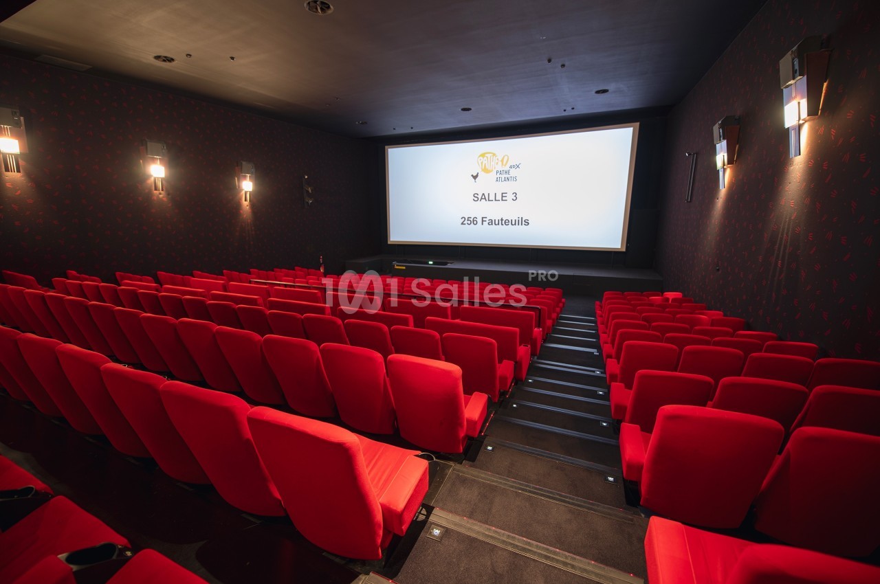 Salle de cinéma vide avec des rangées de fauteuils rouges et un écran affichant ’Salle 3, 256 fauteuils’.