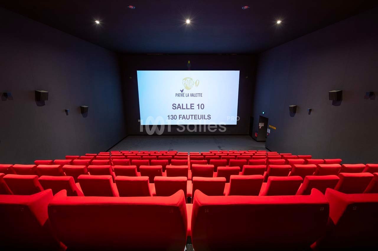 Salle de cinéma vide avec des rangées de fauteuils rouges et un écran affichant ’Salle 10, 130 fauteuils’.