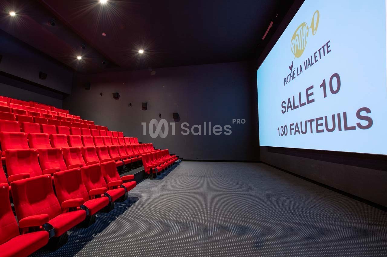 Salle de cinéma vide avec des rangées de fauteuils rouges et un écran affichant ’Salle 10, 130 fauteuils’.