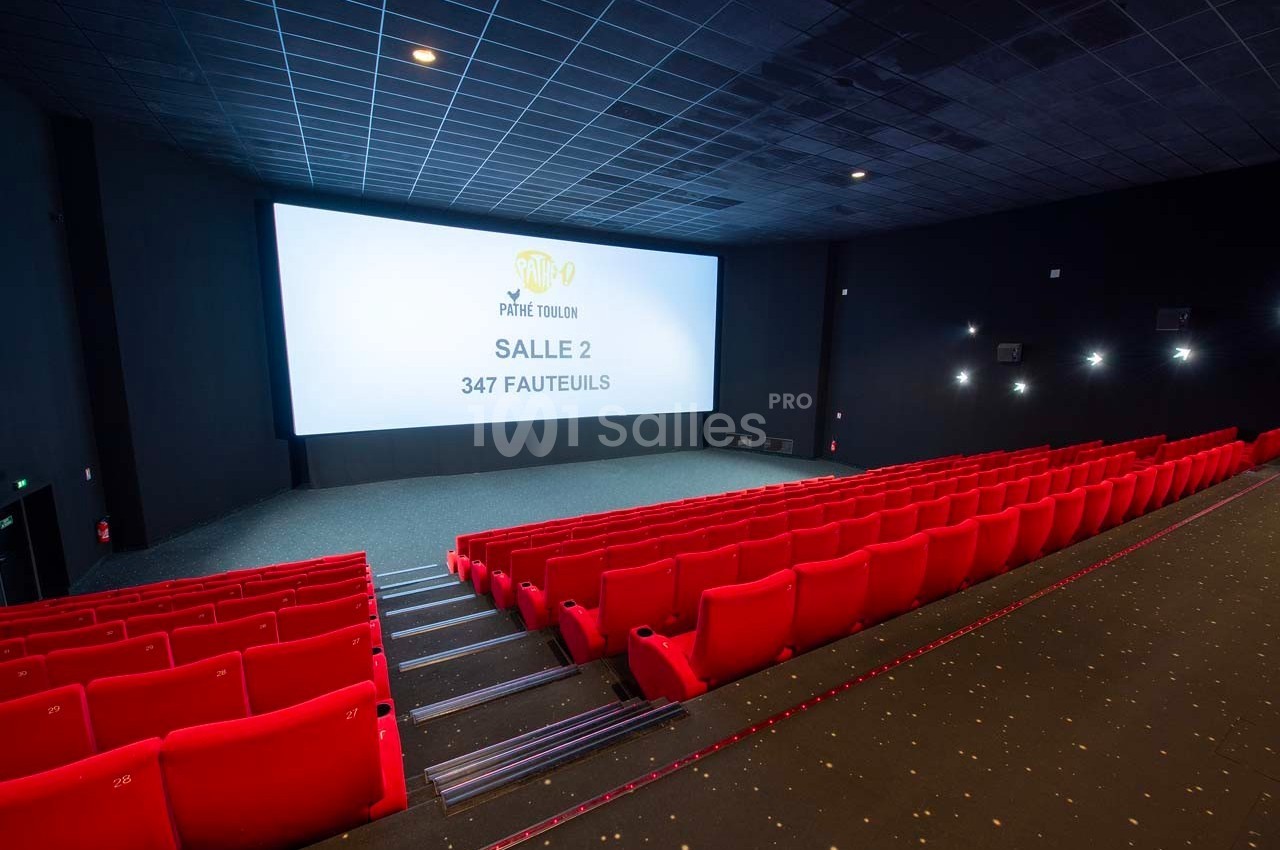 Salle de cinéma vide avec rangées de fauteuils rouges, grand écran affichant ’Salle 2, 347 fauteuils’.