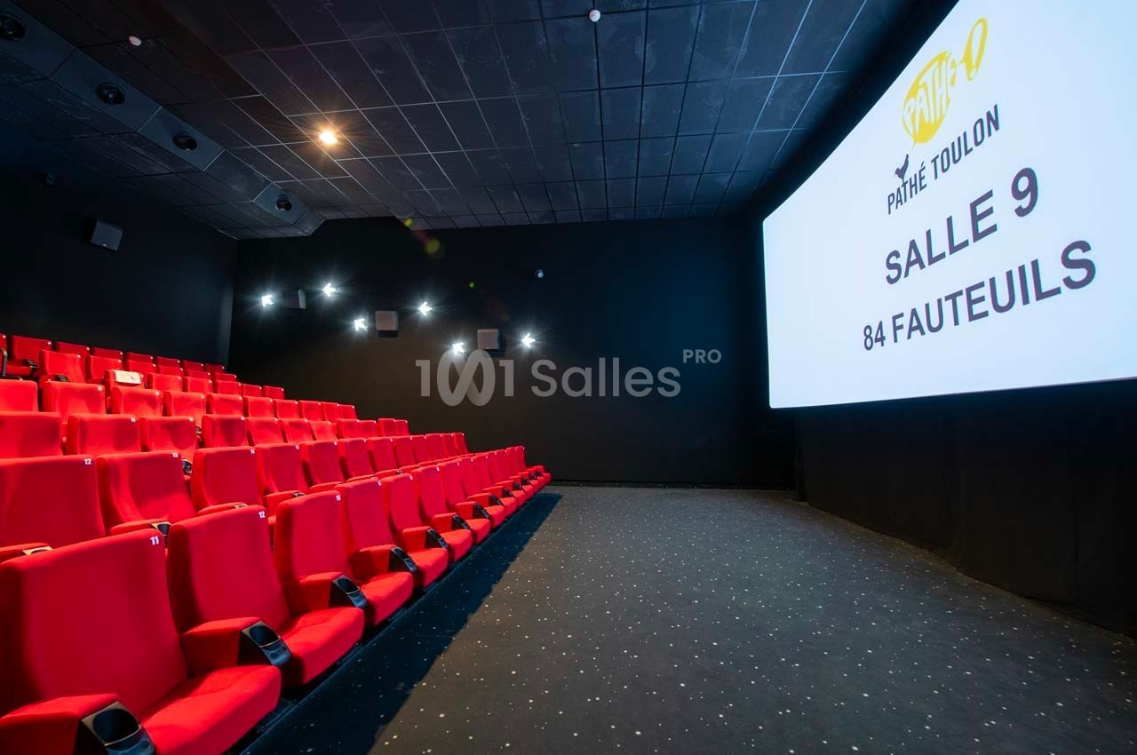 Salle de cinéma avec rangées de sièges rouges et écran affichant ’Pathé Toulon Salle 9, 84 fauteuils’.