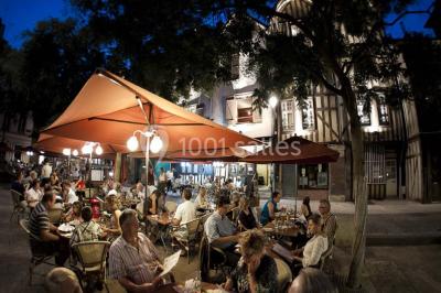 Façade moderne d'un bâtiment avec des murs en verre et acier rouillé, sous un ciel partiellement nuageux.