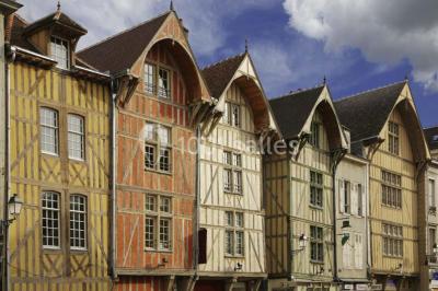 Façade moderne d'un bâtiment avec des murs en verre et acier rouillé, sous un ciel partiellement nuageux.