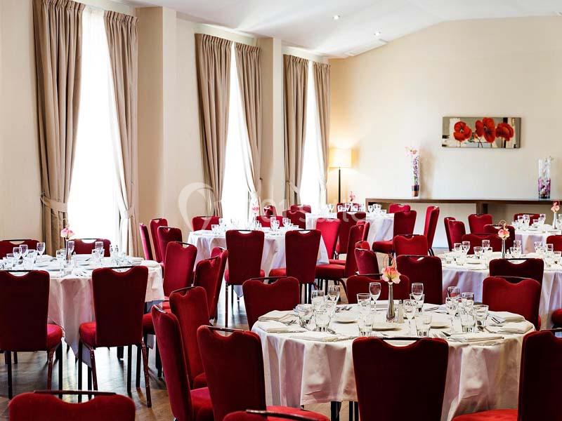 Location salle Aix-en-Provence (Bouches-du-Rhône) - Hôtel Aquabella & Spa #17 Salle de réception avec tables rondes dressées, nappes blanches, chaises rouges et lumière naturelle.