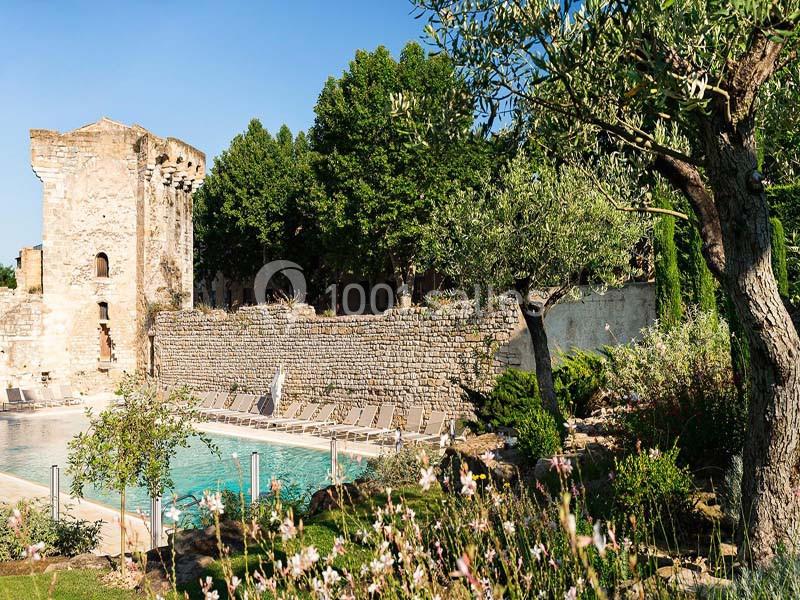 Location salle Aix-en-Provence (Bouches-du-Rhône) - Hôtel Aquabella & Spa #11 Ruines historiques près d'une piscine entourée de végétation et de chaises longues sous un ciel dégagé.