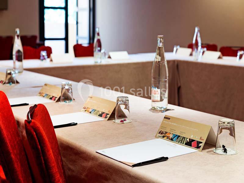 Location salle Aix-en-Provence (Bouches-du-Rhône) - Hôtel Aquabella & Spa #16 Salle de réunion avec tables couvertes de nappes, disposées en U, équipées de blocs-notes, stylos et bouteilles d'eau.