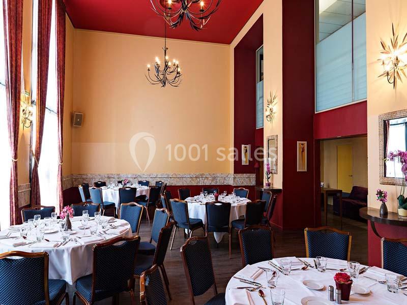 Location salle Aix-en-Provence (Bouches-du-Rhône) - Hôtel Aquabella & Spa #5 Salle de réception élégante avec tables rondes dressées, chaises noires et décorations murales dans des tons rouges et…