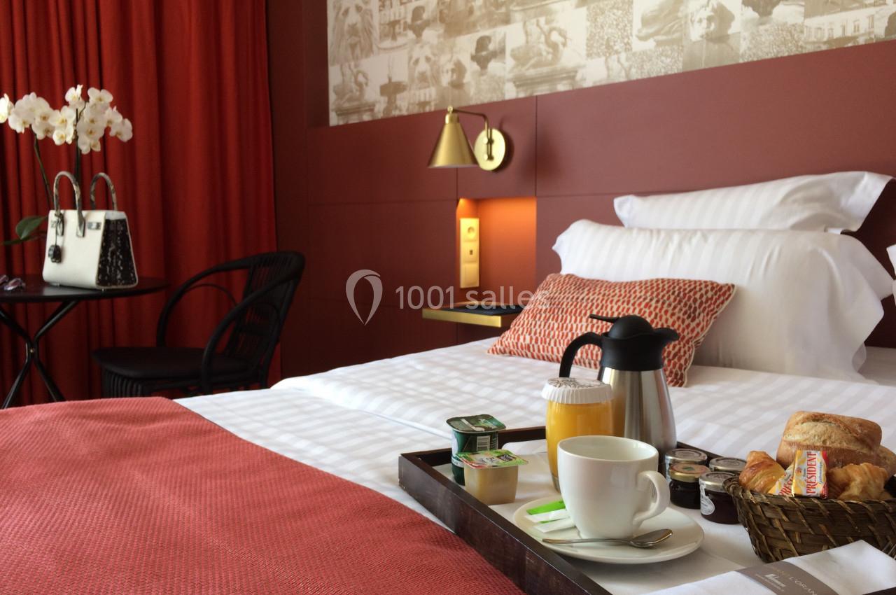 Location salle Aix-en-Provence (Bouches-du-Rhône) - Hôtel Aquabella & Spa #22 Chambre d'hôtel avec lit double, plateau de petit-déjeuner, mur rouge, rideaux assortis et décoration élégante.