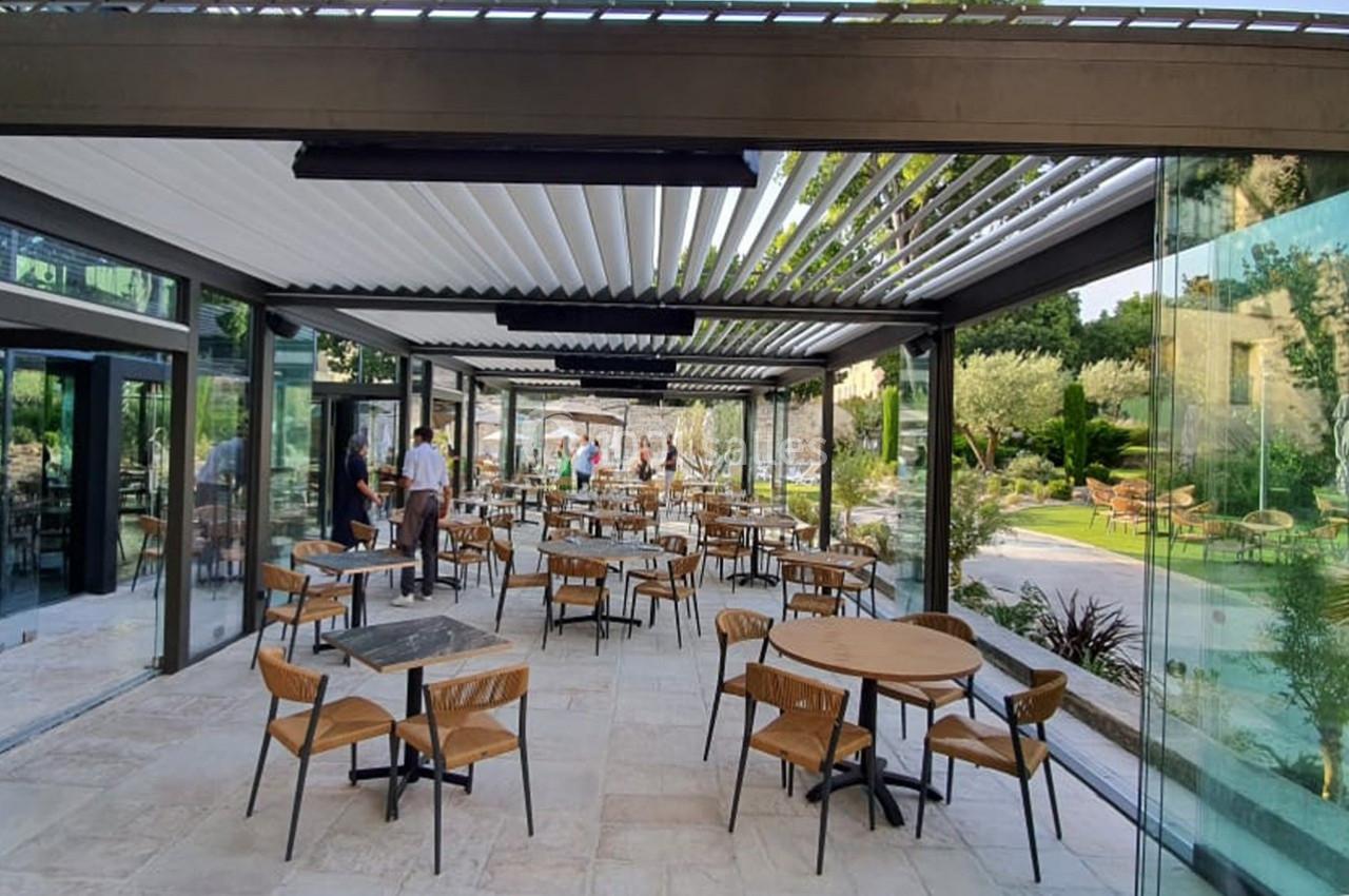 Location salle Aix-en-Provence (Bouches-du-Rhône) - Hôtel Aquabella & Spa #7 Salle de restaurant lumineuse avec grandes baies vitrées, mobilier en bois et vue sur un jardin extérieur.