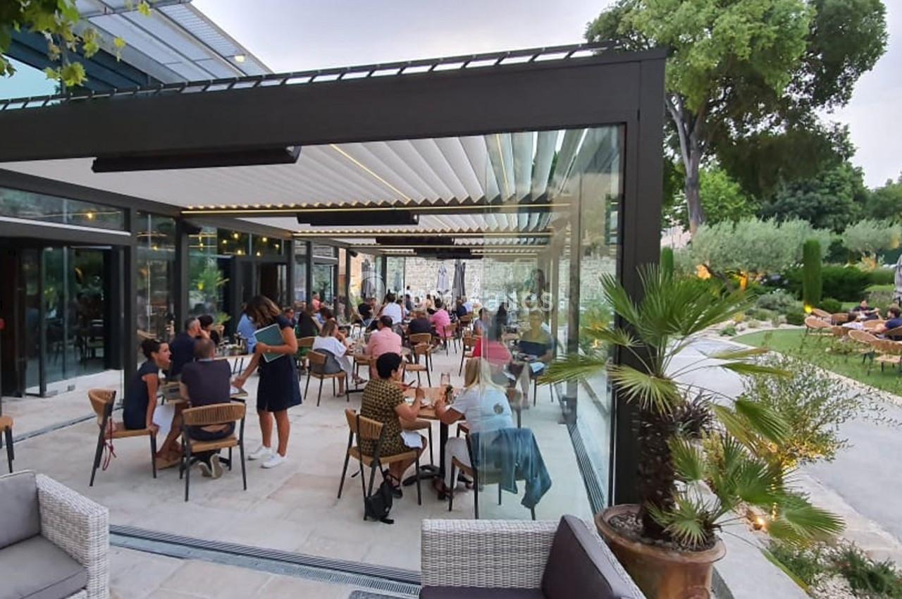Location salle Aix-en-Provence (Bouches-du-Rhône) - Hôtel Aquabella & Spa #8 Terrasse couverte d’un restaurant avec des clients attablés, entourée de végétation et éclairée par la lumière naturelle.