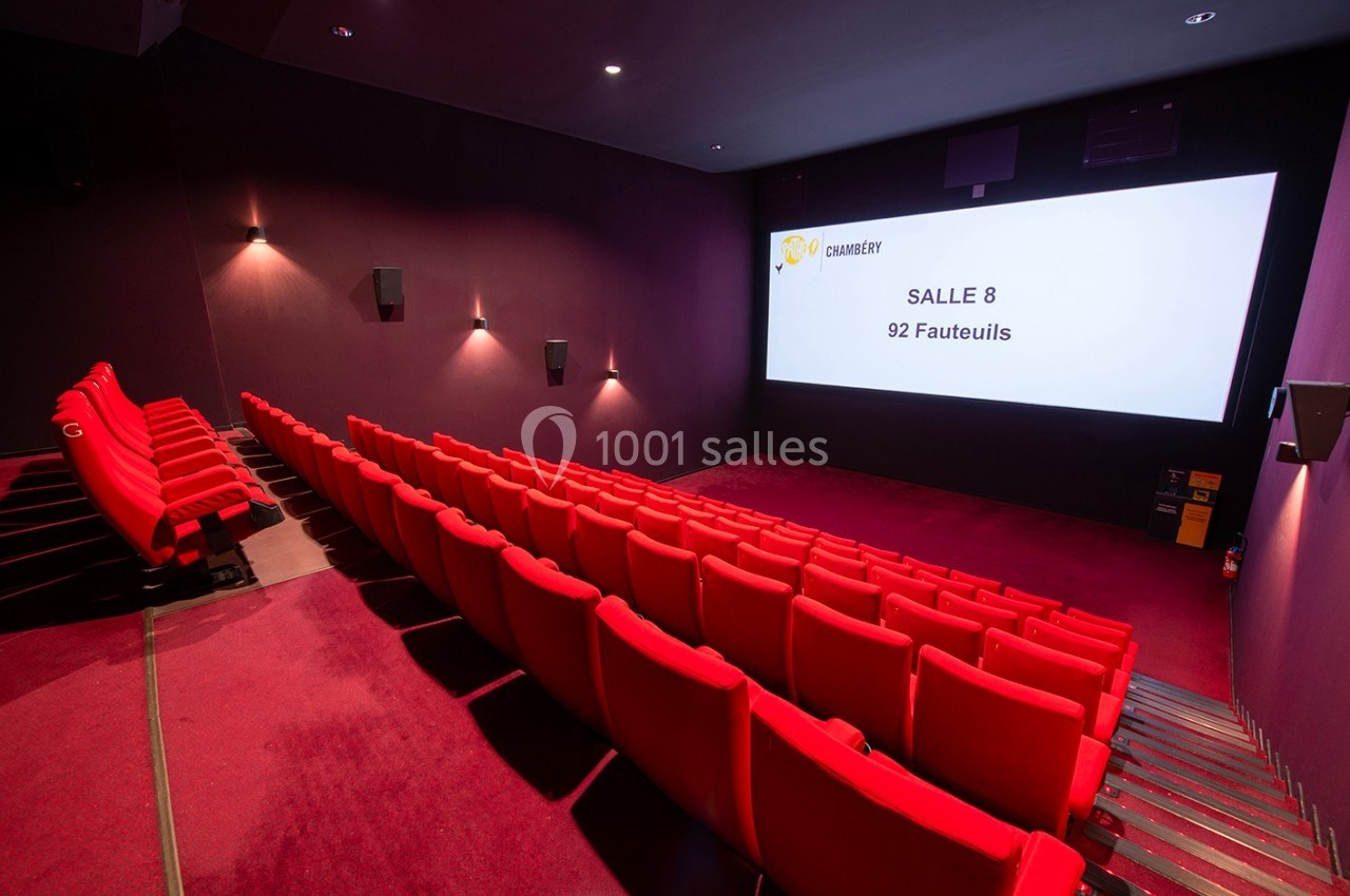 Salle de cinéma vide avec des rangées de fauteuils rouges et un écran affichant ’Salle 8 - 92 fauteuils’.