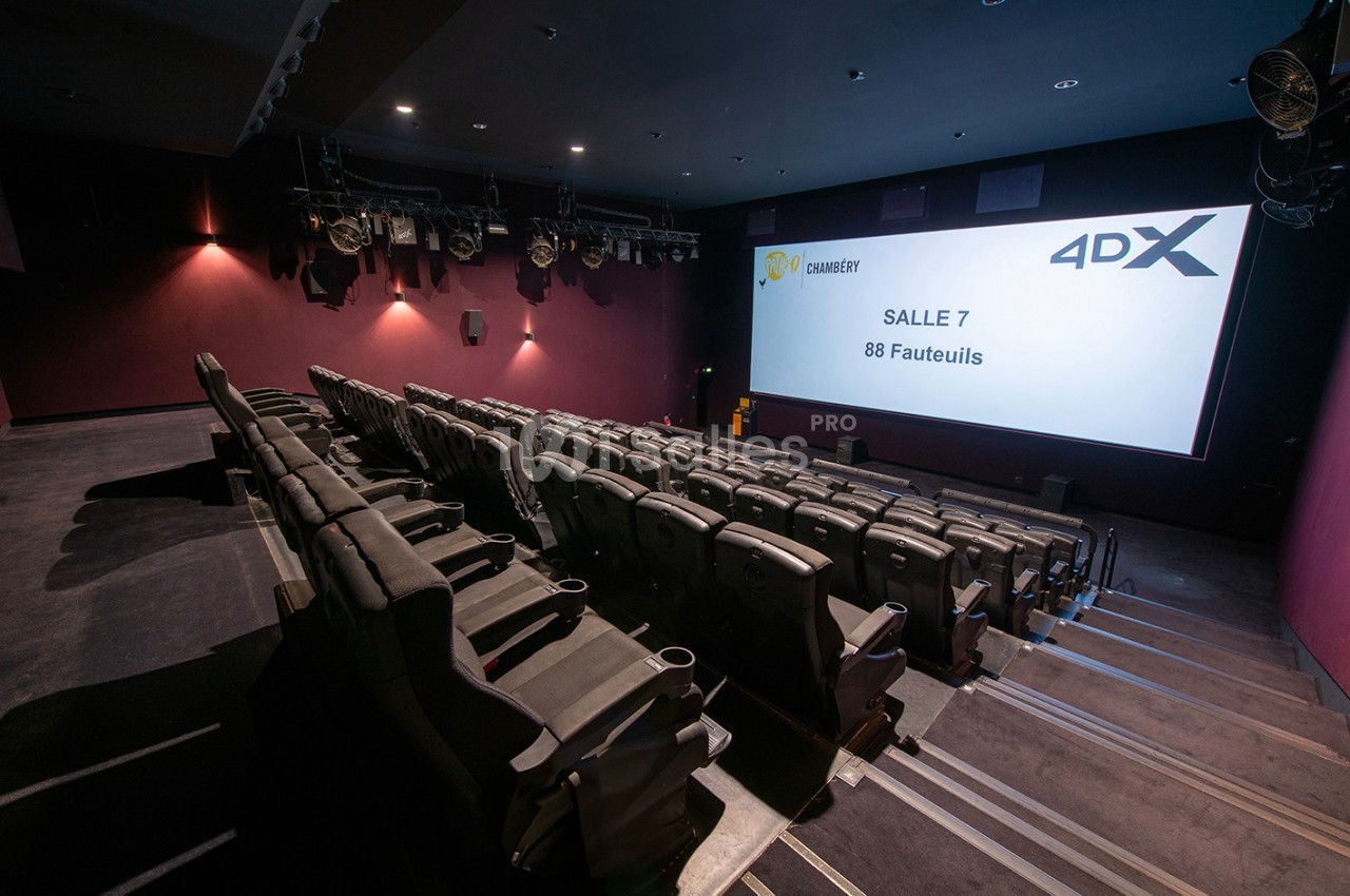 Salle de cinéma équipée de sièges 4DX inclinables, écran allumé affichant ’Salle 7, 88 fauteuils’.