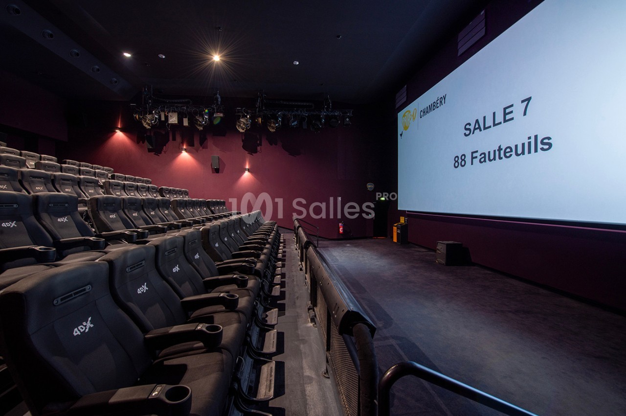Salle de cinéma vide avec 88 fauteuils en rangées, écran affichant ’Salle 7’ et éclairage tamisé.