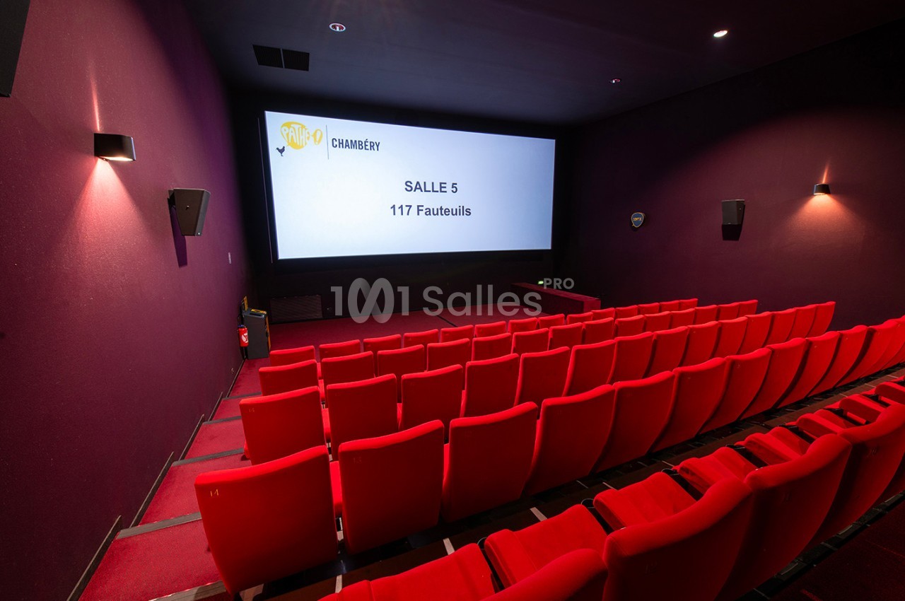 Salle de cinéma vide avec des rangées de fauteuils rouges et un écran affichant ’Salle 5 - 117 Fauteuils’.