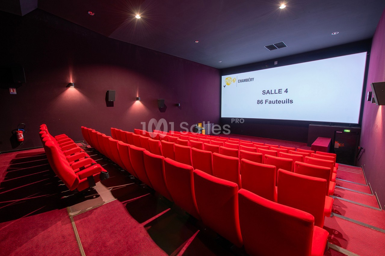 Salle de cinéma vide avec des rangées de fauteuils rouges et un écran affichant ’Salle 4 - 86 Fauteuils’.