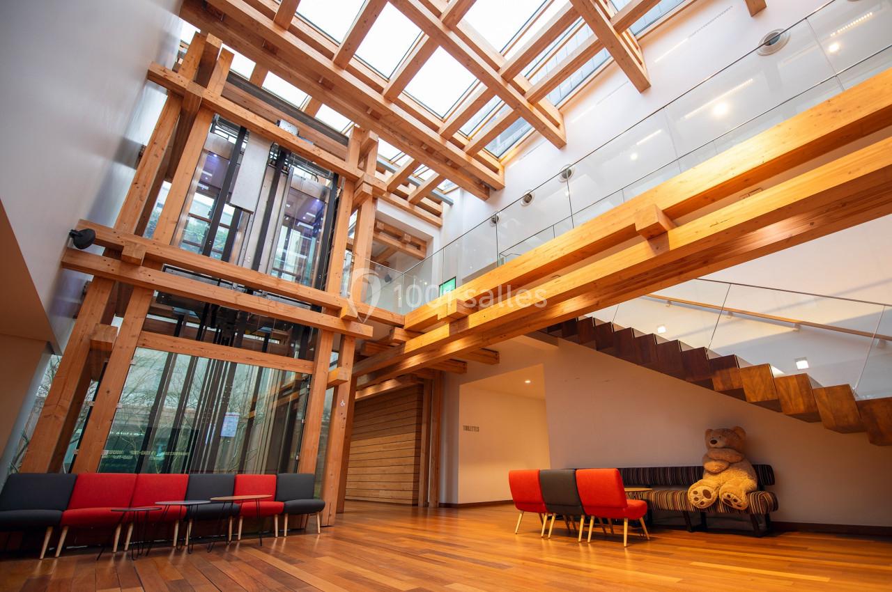 Location salle Paris 13 (Paris) - Pathé Les Fauvettes #9 Intérieur lumineux avec structure en bois, escalier moderne, sièges colorés et un grand ours en peluche.