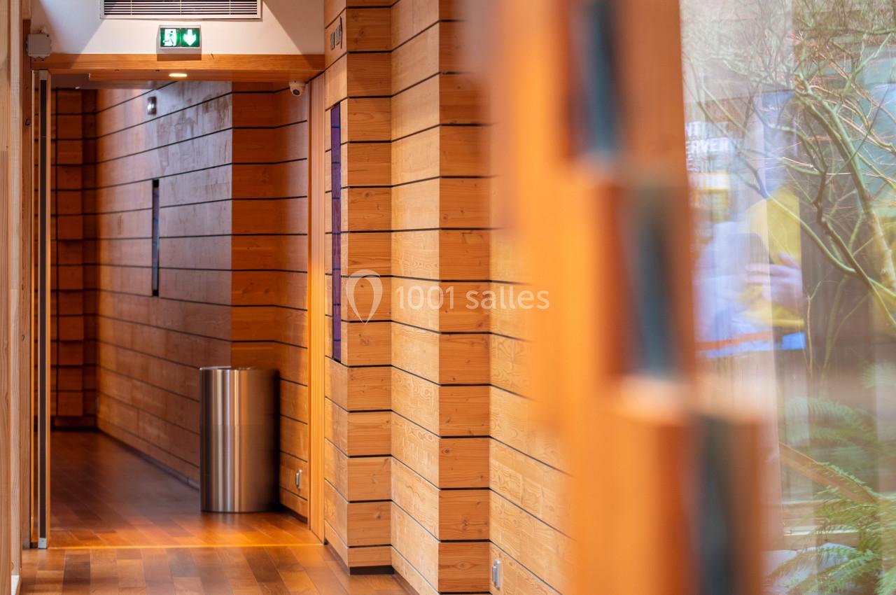 Location salle Paris 13 (Paris) - Pathé Les Fauvettes #11 Couloir en bois avec parquet, murs lambrissés, poubelle métallique et lumière naturelle entrant par une grande fenêtre.