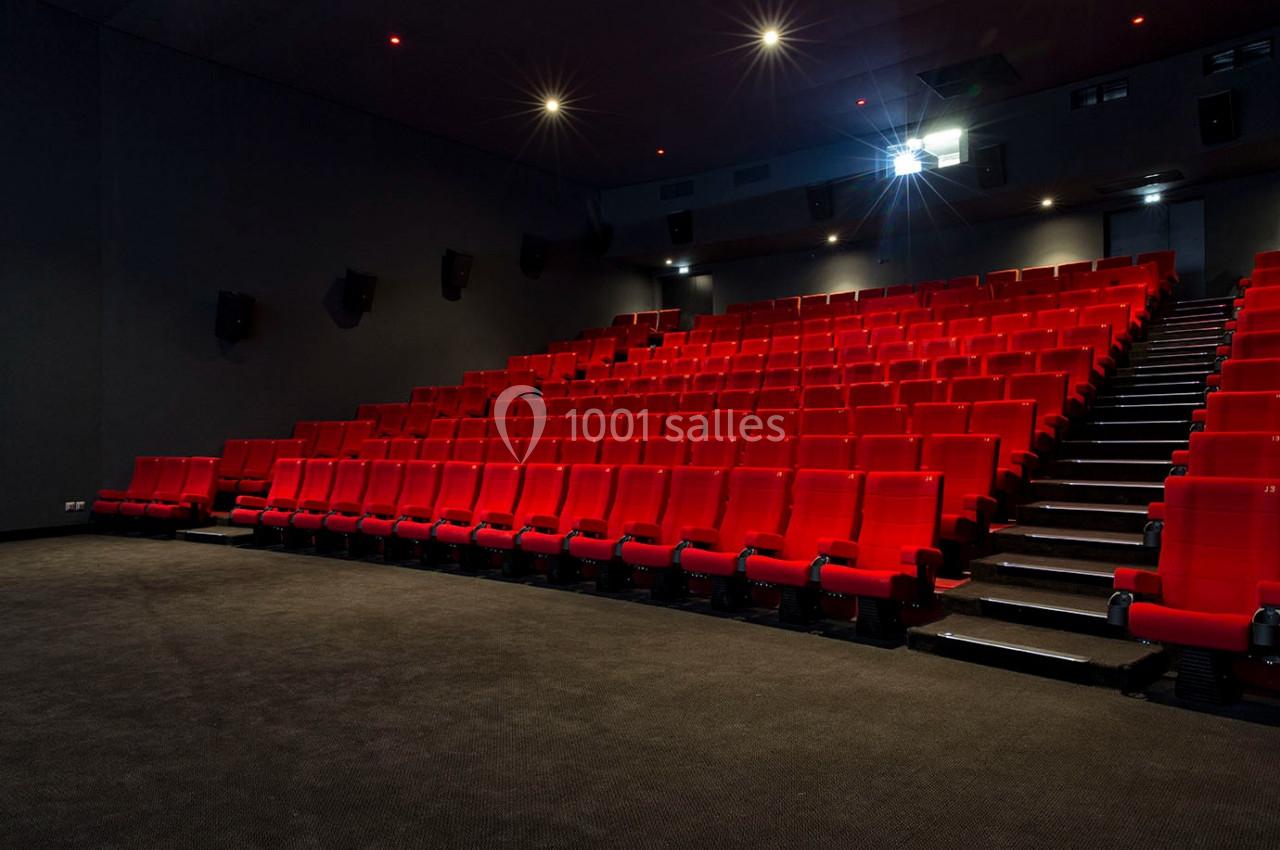 Location salle Paris 13 (Paris) - Pathé Les Fauvettes #3 Salle de cinéma vide avec des rangées de sièges rouges et un projecteur allumé.