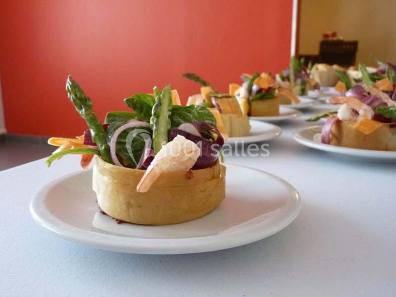 Assiette contenant une entrée composée de crevettes, légumes frais et asperges, présentée dans une base croustillante.