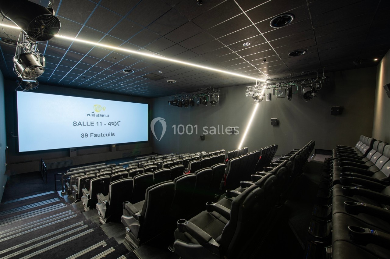 Salle de cinéma vide avec rangées de fauteuils noirs, écran allumé affichant ’Salle 411 - 4DX, 89 fauteuils’.