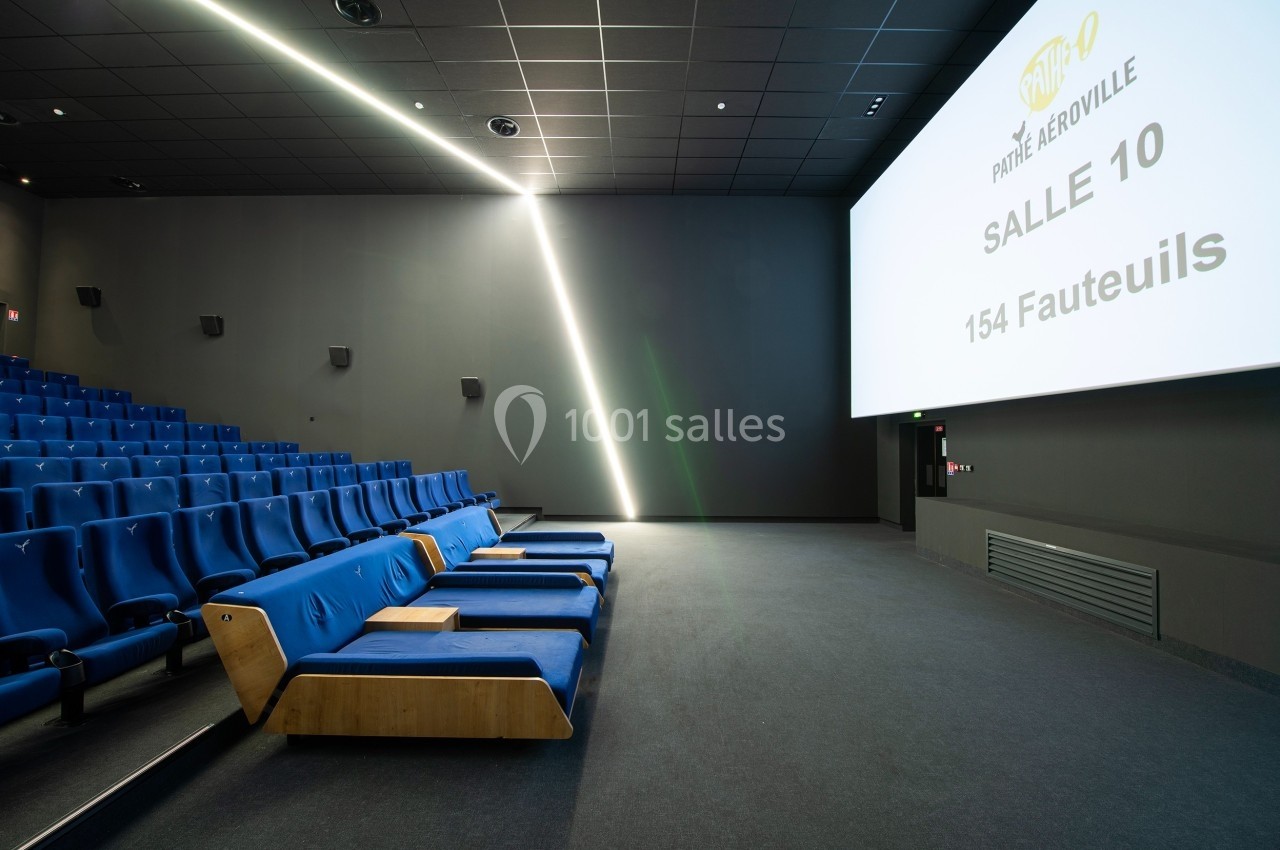 Salle de cinéma moderne avec sièges bleus, fauteuils inclinables en bois et écran affichant des informations sur la salle.