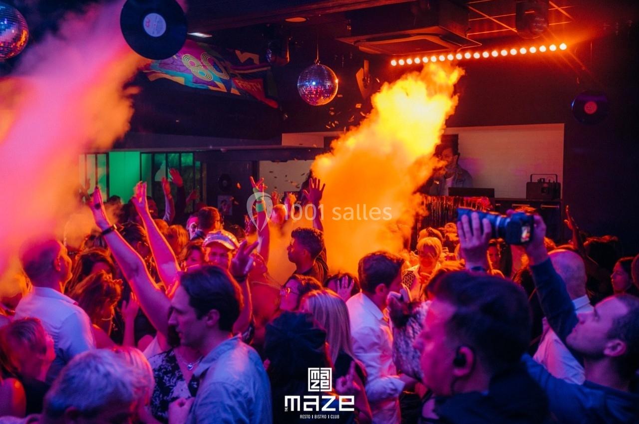 Foule dans une discothèque animée avec jeux de lumière colorés et fumée, ambiance festive et dansante.