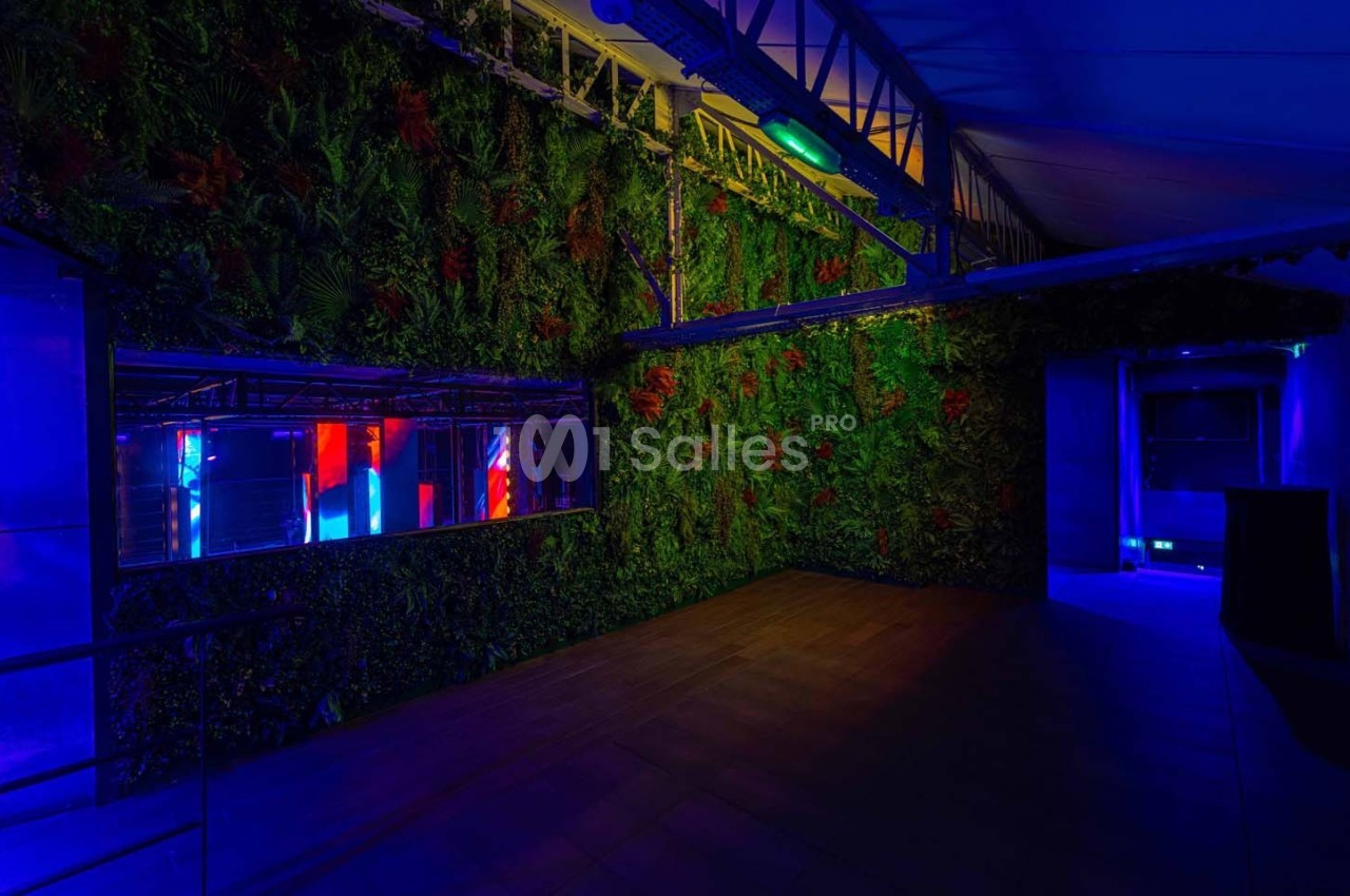 Mur végétal éclairé par des lumières colorées dans un espace intérieur à l'ambiance tamisée et moderne.