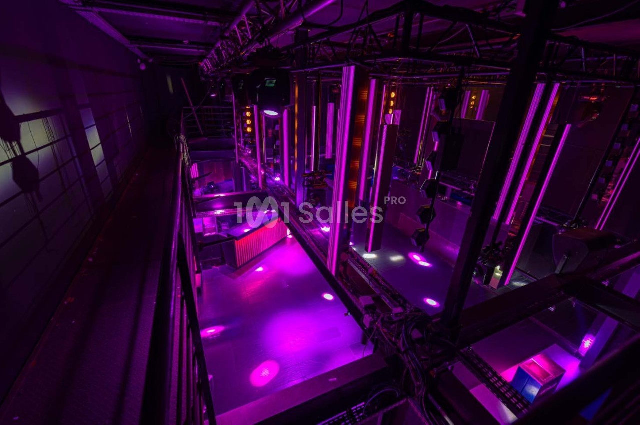 Vue plongeante d'une salle équipée de lumières violettes et de structures métalliques pour des événements ou spectacles.