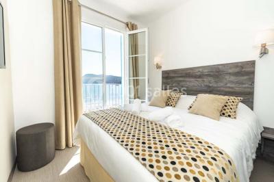 Miniature Location salle La Seyne-sur-Mer (Var) - Hôtel Restaurant George Sand #37 Chambre lumineuse avec lit double, décor beige et fenêtre ouverte offrant une vue sur la mer et les collines.