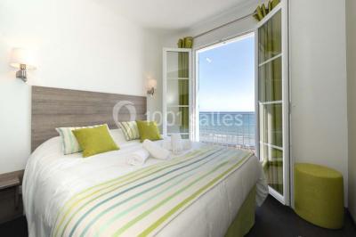 Miniature Location salle La Seyne-sur-Mer (Var) - Hôtel Restaurant George Sand #36 Chambre lumineuse avec lit double, décor beige et fenêtre ouverte offrant une vue sur la mer et les collines.