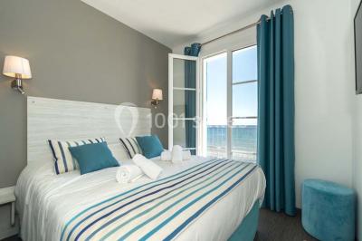 Miniature Location salle La Seyne-sur-Mer (Var) - Hôtel Restaurant George Sand #33 Chambre lumineuse avec lit double, décor beige et fenêtre ouverte offrant une vue sur la mer et les collines.