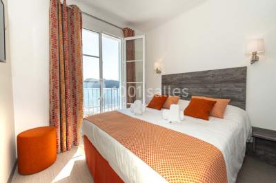 Miniature Location salle La Seyne-sur-Mer (Var) - Hôtel Restaurant George Sand #35 Chambre lumineuse avec lit double, décor beige et fenêtre ouverte offrant une vue sur la mer et les collines.