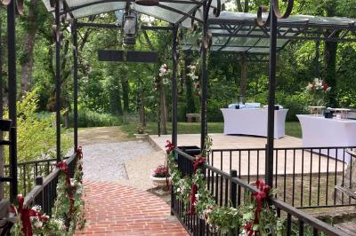 Tentes blanches installées sur une pelouse entourée d'arbres, avec tables et bottes de foin disposées en extérieur.