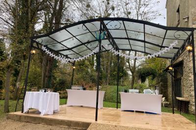 Tentes blanches installées sur une pelouse entourée d'arbres, avec tables et bottes de foin disposées en extérieur.