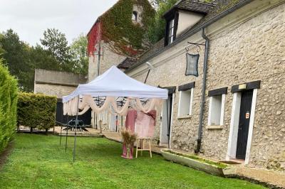 Tentes blanches installées sur une pelouse entourée d'arbres, avec tables et bottes de foin disposées en extérieur.