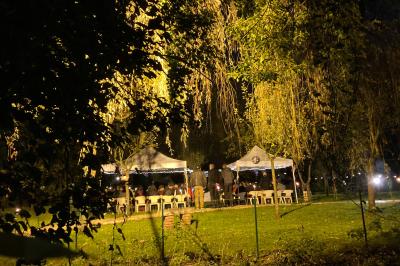 Tentes blanches installées sur une pelouse entourée d'arbres, avec tables et bottes de foin disposées en extérieur.