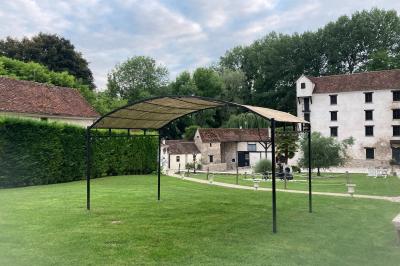 Tentes blanches installées sur une pelouse entourée d'arbres, avec tables et bottes de foin disposées en extérieur.