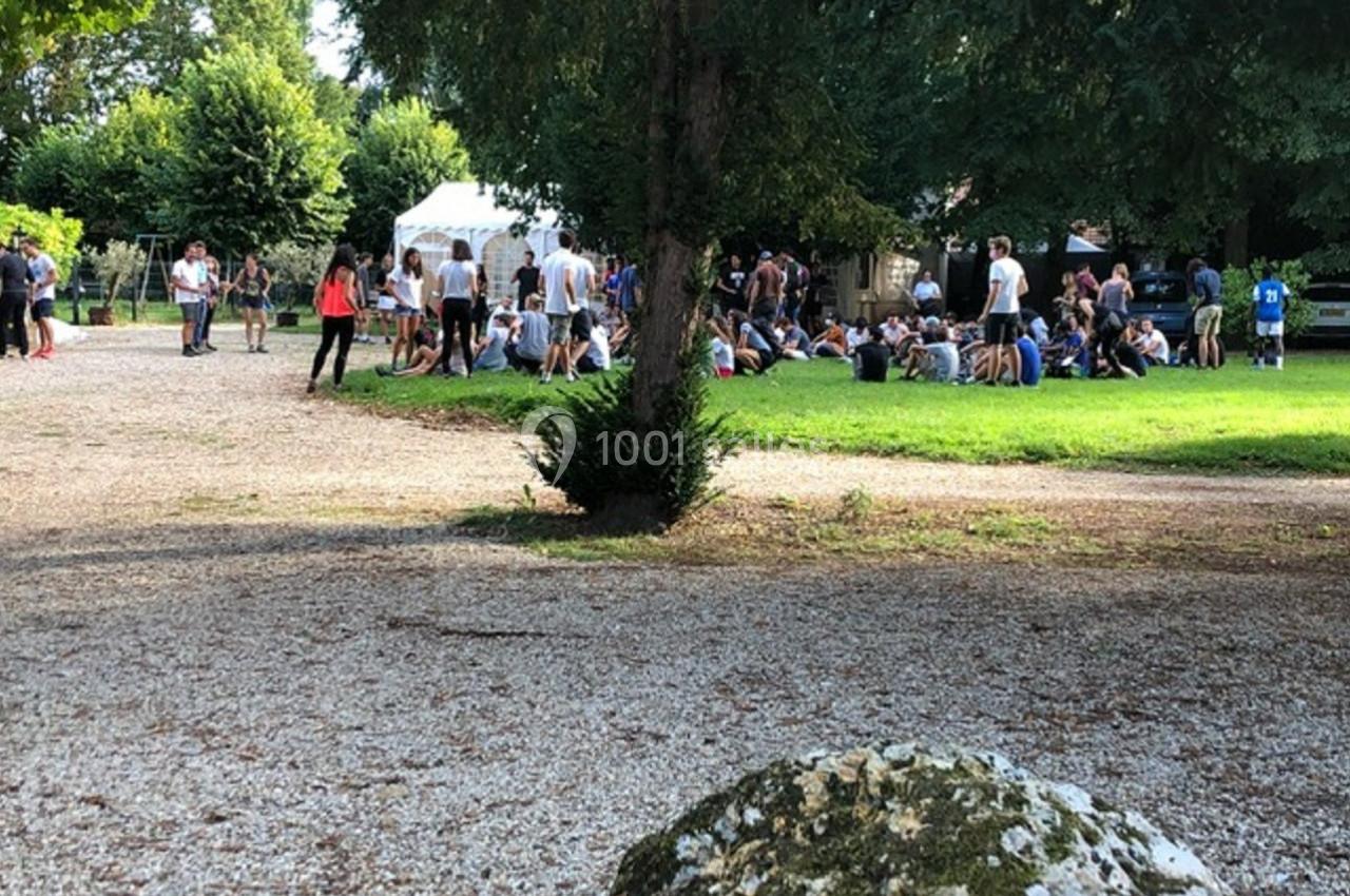 Un groupe de personnes assises et debout dans un parc, entouré d'arbres et de pelouses.