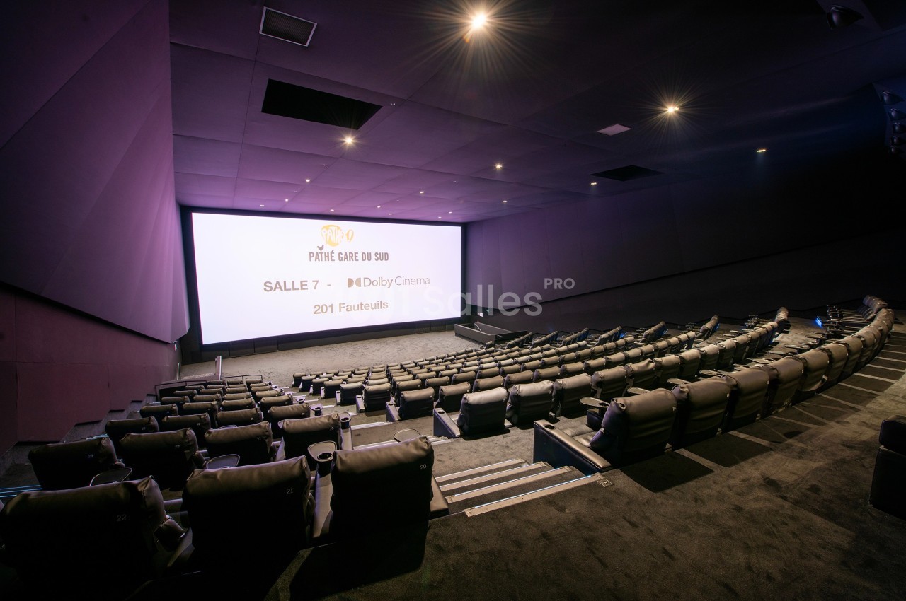 Salle de cinéma moderne avec des fauteuils inclinables, écran large et éclairage tamisé.
