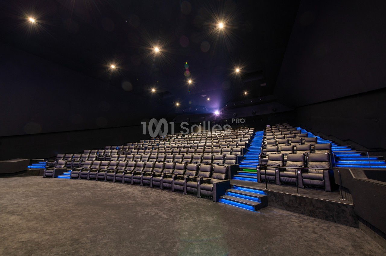 Salle de cinéma vide avec rangées de sièges noirs et éclairage bleu sur les marches.