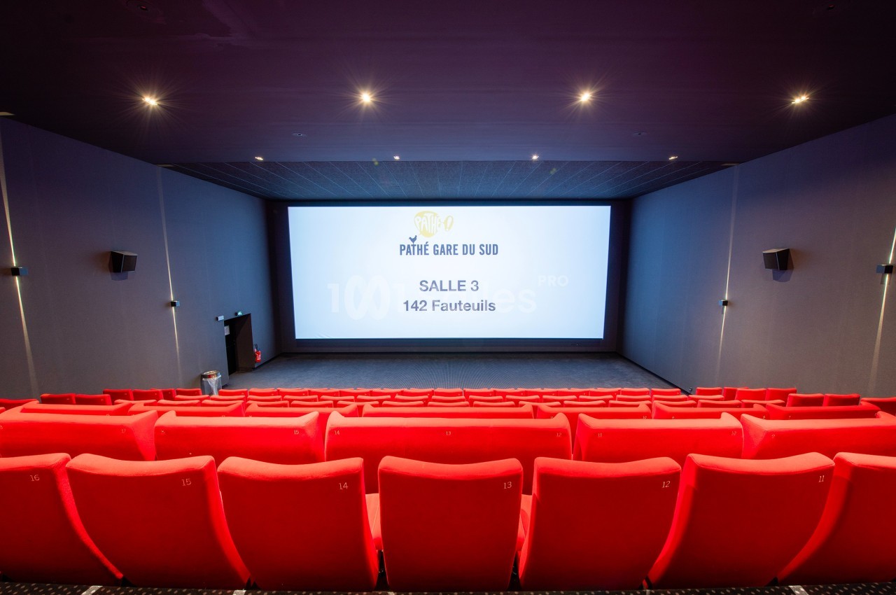 Salle de cinéma vide avec des rangées de sièges rouges et un écran affichant ’Pathé Gare du Sud, Salle 3, 142 fauteuils’.
