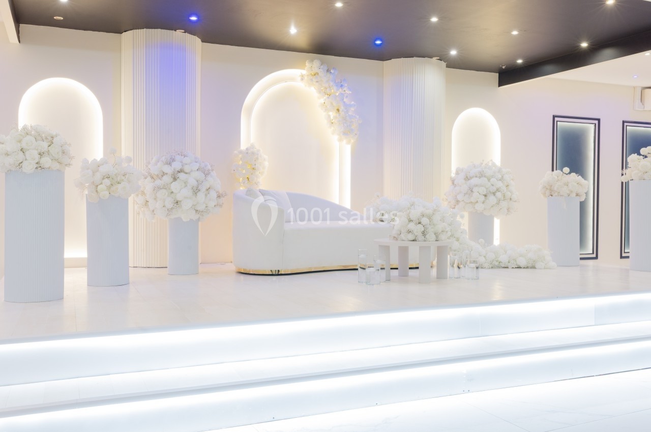 Décor lumineux et élégant avec un canapé blanc entouré de colonnes et de bouquets de fleurs blanches.