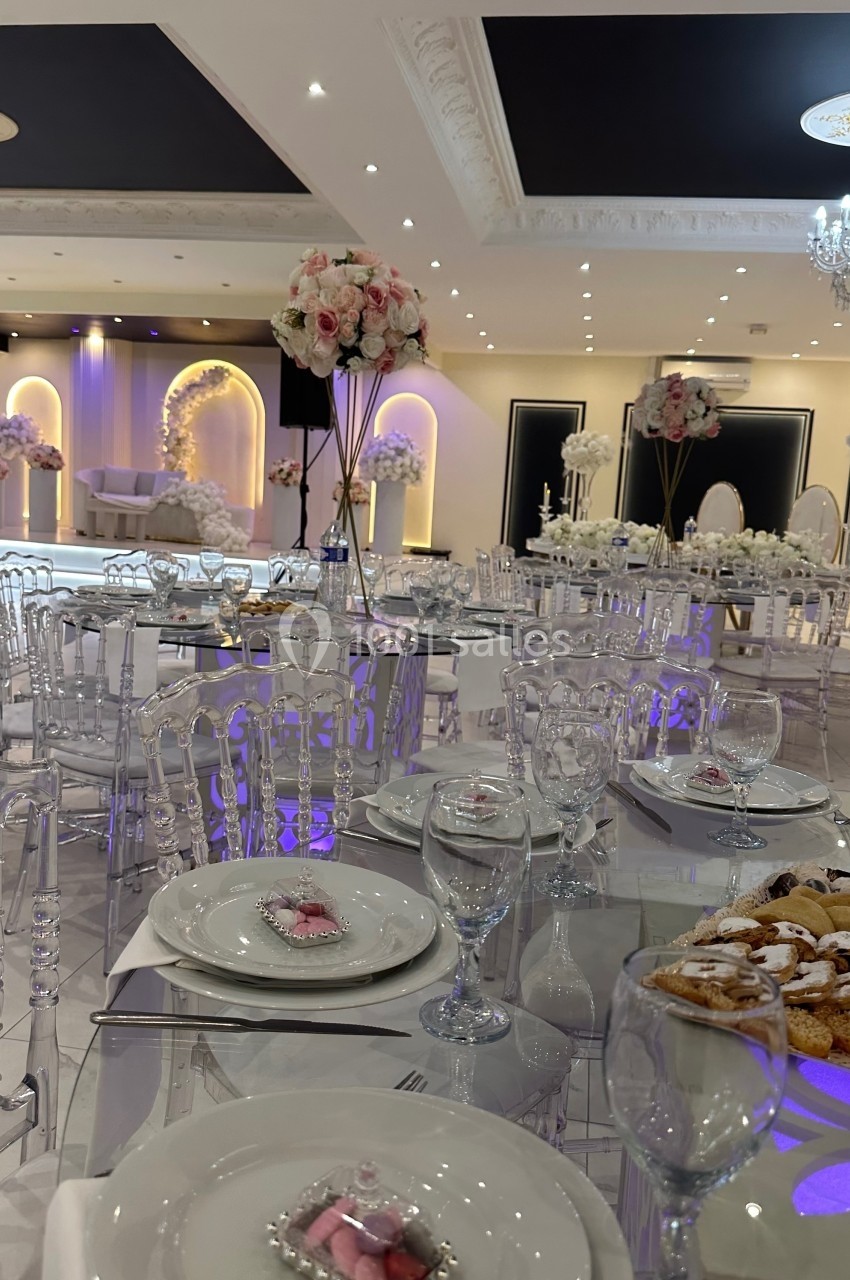 Salle de réception élégante avec tables dressées, décorations florales et éclairage tamisé.
