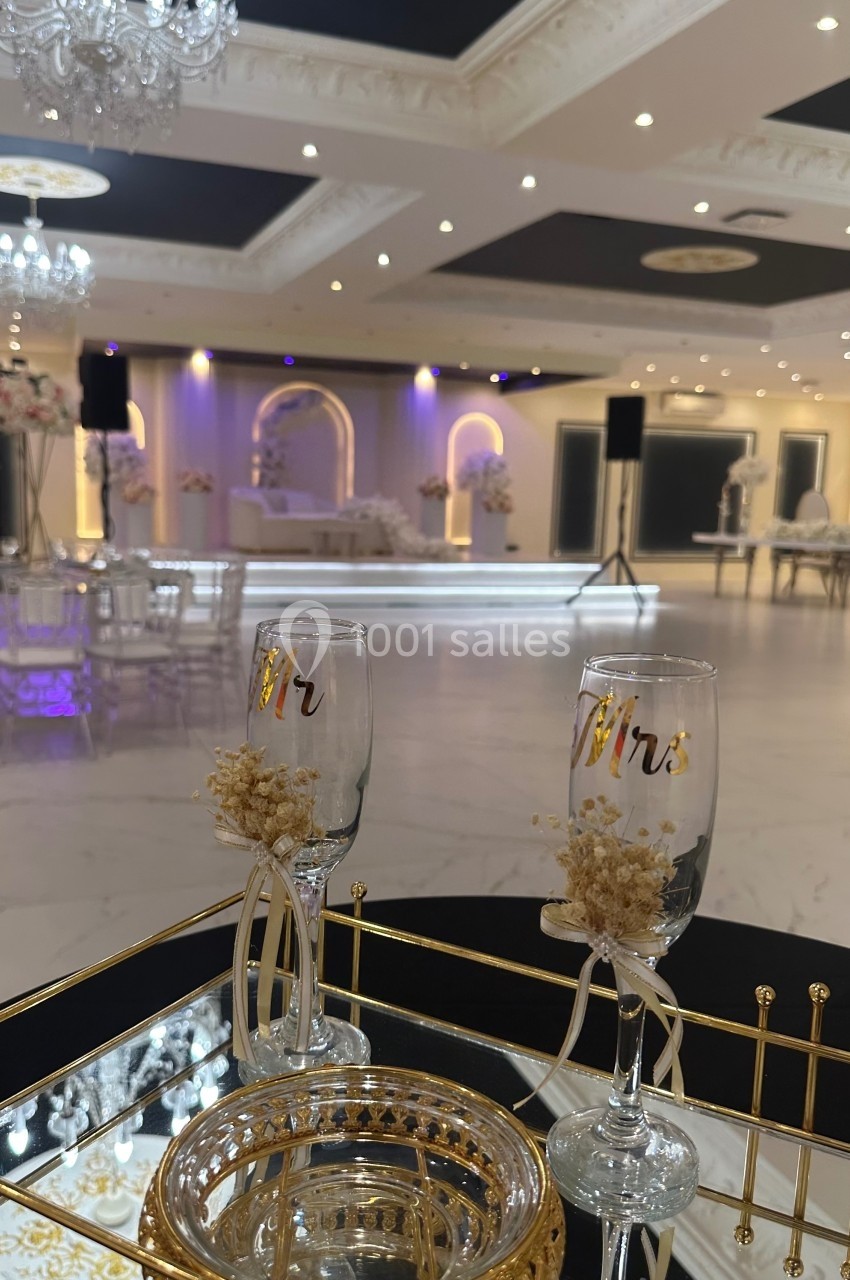 Deux flûtes gravées ’Mr’ posées sur une table décorative dans une salle de réception élégante et lumineuse.