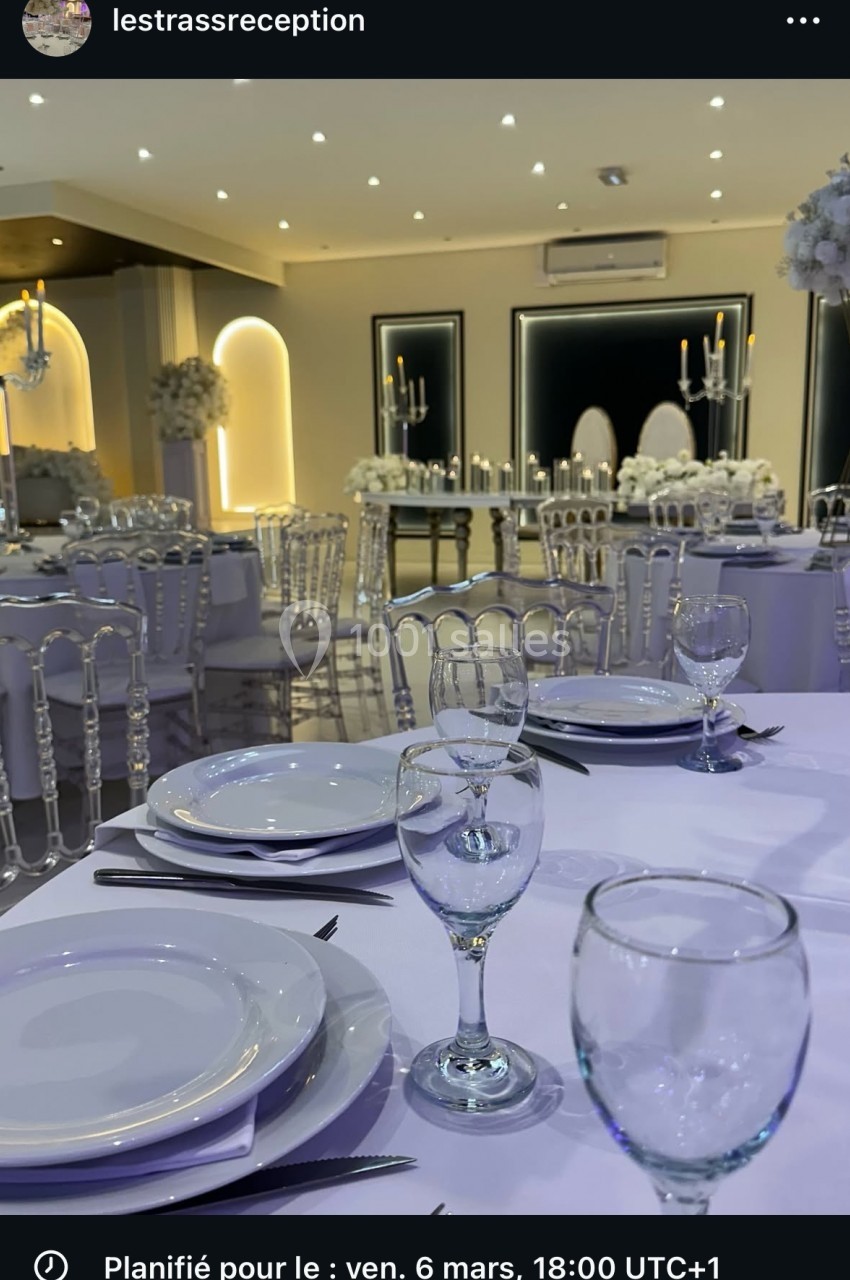 Salle de réception élégamment dressée avec des tables rondes, nappes blanches, vaisselle raffinée et décor floral.