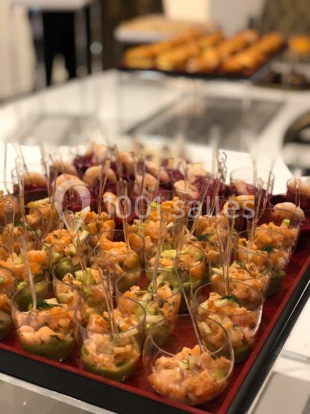 Plateau de verrines contenant des préparations colorées à base de saumon et légumes, disposé sur une table.