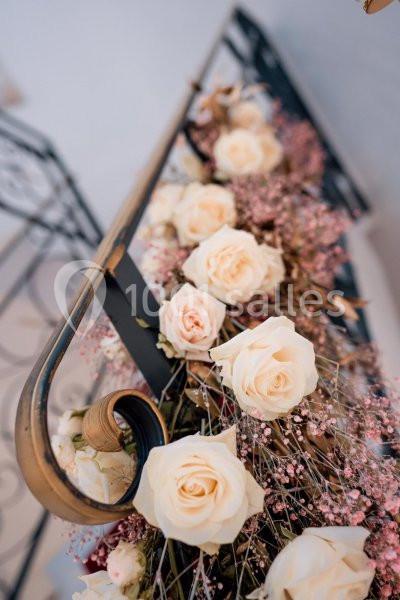 Roses blanches et fleurs roses décorant une rampe en métal noir dans un cadre élégant.