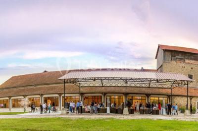 Miniature Location salle Lieusaint (Seine-et-Marne) - La Ferme de Villepecle #3 Groupe de personnes réunies en extérieur sous une structure métallique, devant un bâtiment en pierre et bois.